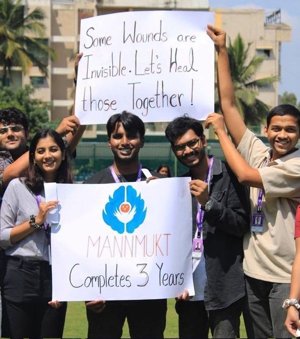 Students holding a sign reading Some wounds are invisible, let's heal those together, and MannMukt completes 3 years